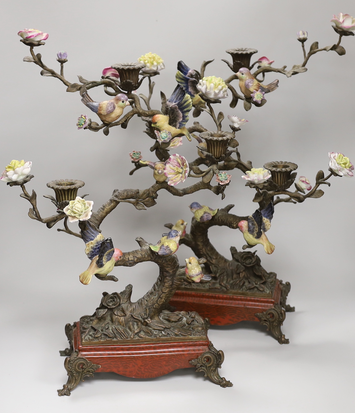 A pair of Victorian style bronzed metal and porcelain three branch candelabra, modelled as birds among branches, each 51cm high
